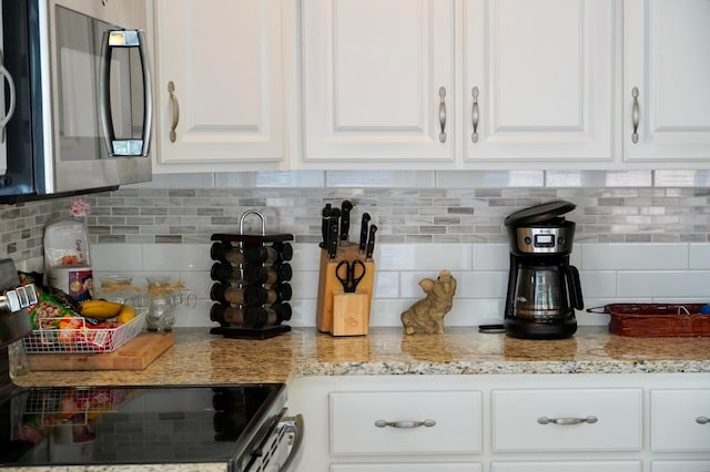 kitchen with white cabinets, backsplash, and light stone counters