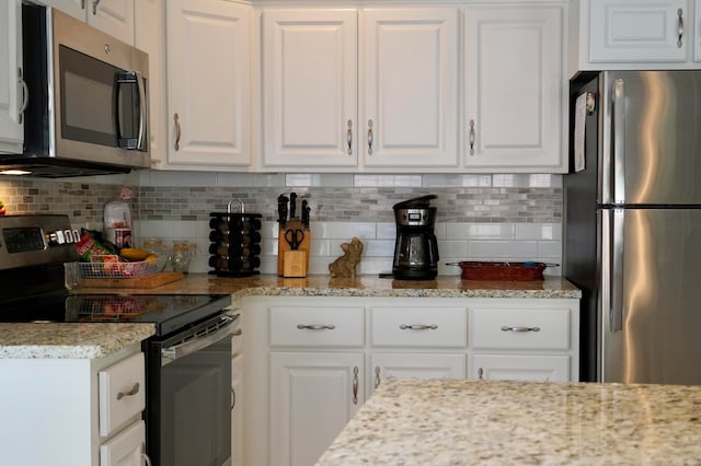 kitchen with white cabinets, decorative backsplash, appliances with stainless steel finishes, and light stone counters