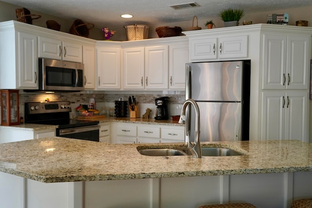 kitchen with white cabinetry, appliances with stainless steel finishes, backsplash, sink, and a kitchen breakfast bar