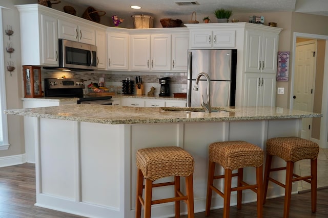 kitchen featuring stainless steel appliances, sink, tasteful backsplash, hardwood / wood-style floors, and white cabinets