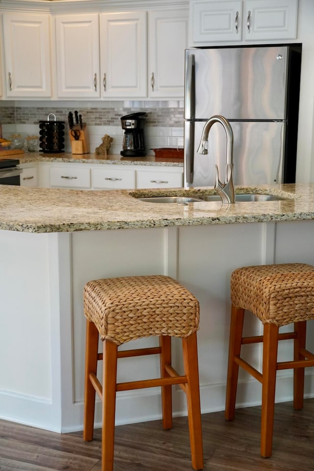 kitchen featuring a kitchen bar, white cabinetry, and decorative backsplash