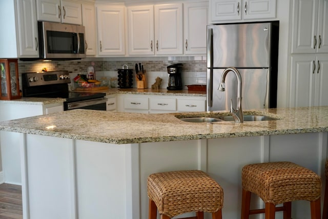 kitchen with white cabinets, a kitchen breakfast bar, and appliances with stainless steel finishes