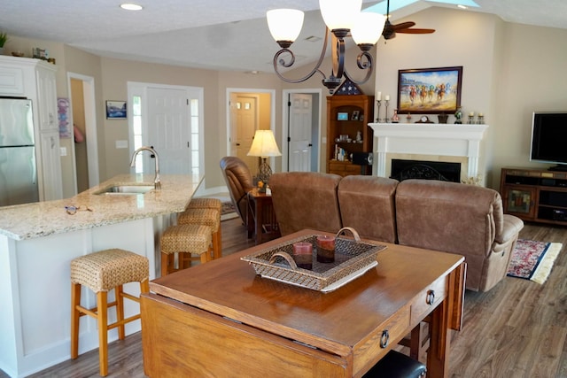 dining room featuring wood-type flooring, a textured ceiling, sink, and vaulted ceiling