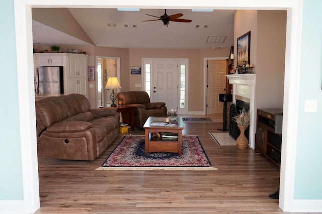 living room featuring light hardwood / wood-style flooring, lofted ceiling, and ceiling fan