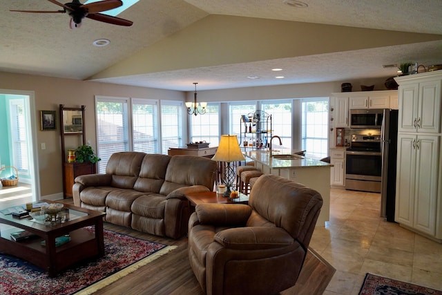 living room featuring plenty of natural light, sink, a textured ceiling, and vaulted ceiling