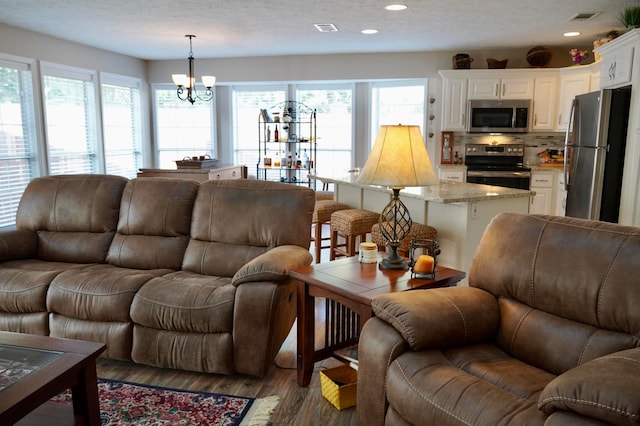 living room featuring a textured ceiling, dark hardwood / wood-style floors, and a chandelier