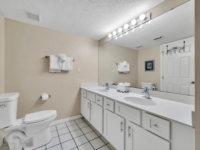 bathroom with tile patterned flooring, vanity, a textured ceiling, and toilet