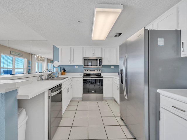 kitchen featuring sink, light tile patterned floors, a textured ceiling, white cabinets, and appliances with stainless steel finishes