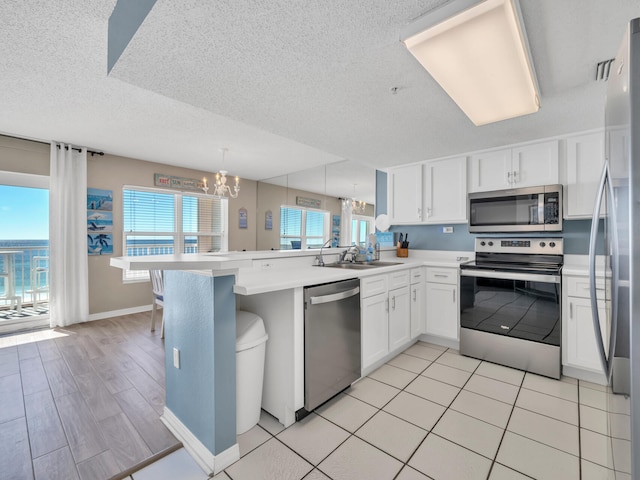 kitchen featuring kitchen peninsula, stainless steel appliances, white cabinetry, and a healthy amount of sunlight