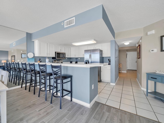 kitchen with white cabinets, a kitchen breakfast bar, light hardwood / wood-style floors, and kitchen peninsula