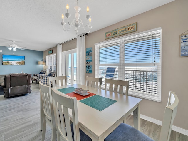 dining area featuring a textured ceiling, light hardwood / wood-style flooring, a healthy amount of sunlight, and ceiling fan with notable chandelier