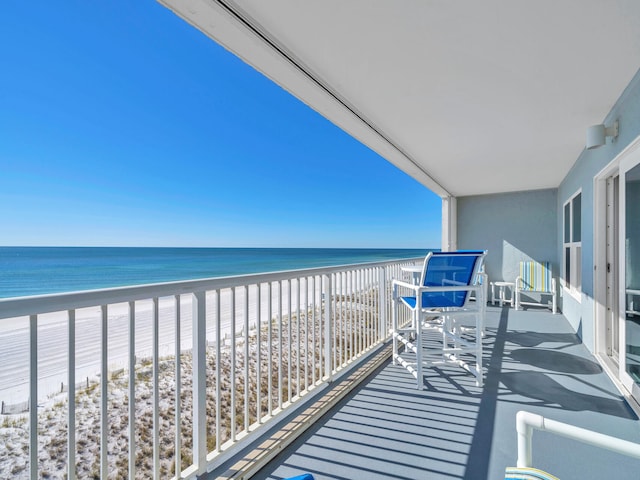 balcony featuring a view of the beach and a water view