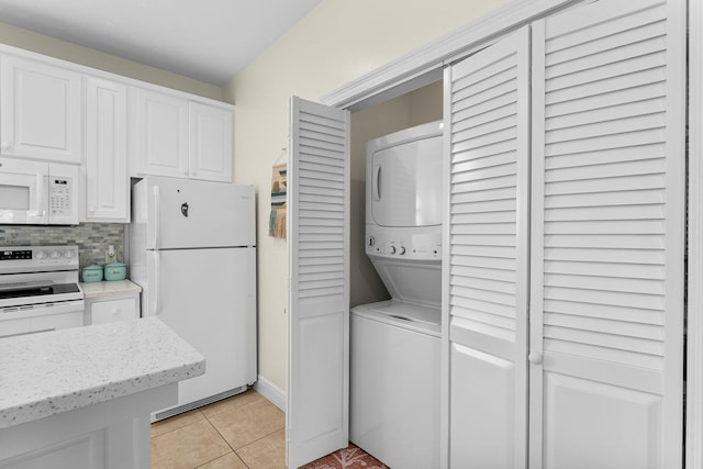 laundry area with light tile patterned floors and stacked washer / drying machine