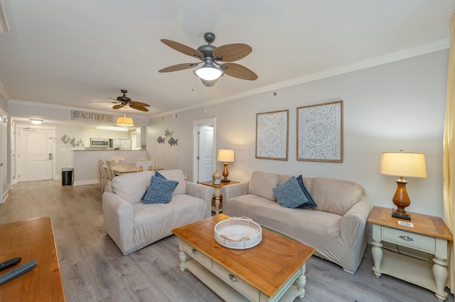 living room featuring light hardwood / wood-style floors, ceiling fan, and ornamental molding