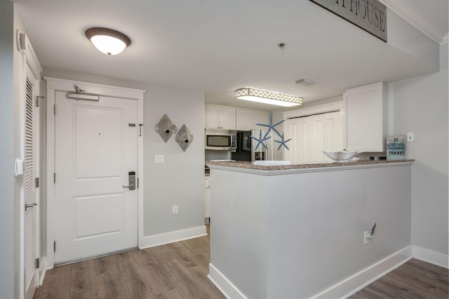 kitchen with kitchen peninsula, white cabinetry, and light wood-type flooring