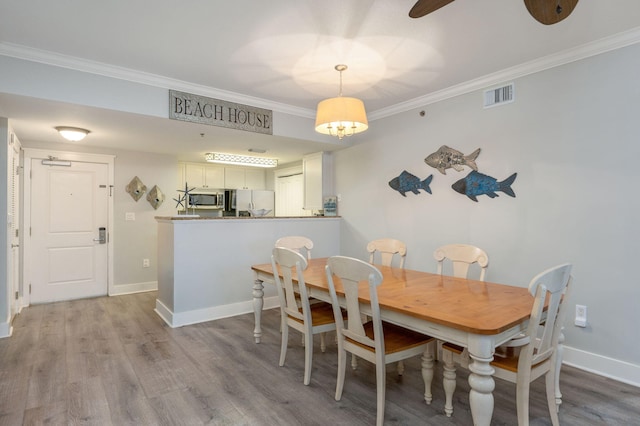 dining space with ceiling fan, crown molding, and light hardwood / wood-style flooring