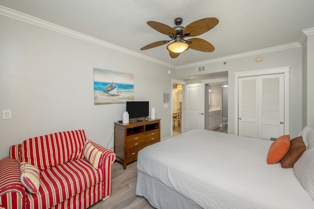 bedroom with ceiling fan, light hardwood / wood-style flooring, crown molding, ensuite bathroom, and a closet