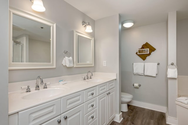 bathroom with an enclosed shower, vanity, toilet, and wood-type flooring