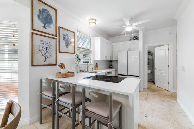 kitchen with white cabinets, plenty of natural light, white refrigerator, and kitchen peninsula