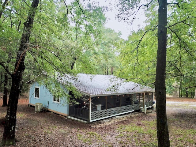 rear view of property featuring a sunroom and central AC