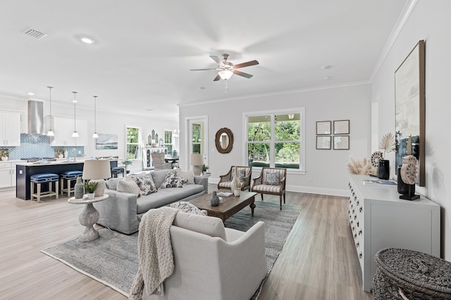 living room featuring ornamental molding, ceiling fan, light hardwood / wood-style flooring, and plenty of natural light