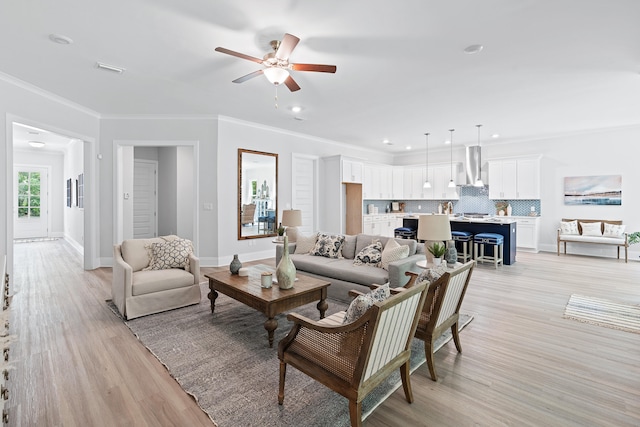 living room featuring ceiling fan, ornamental molding, and light hardwood / wood-style flooring