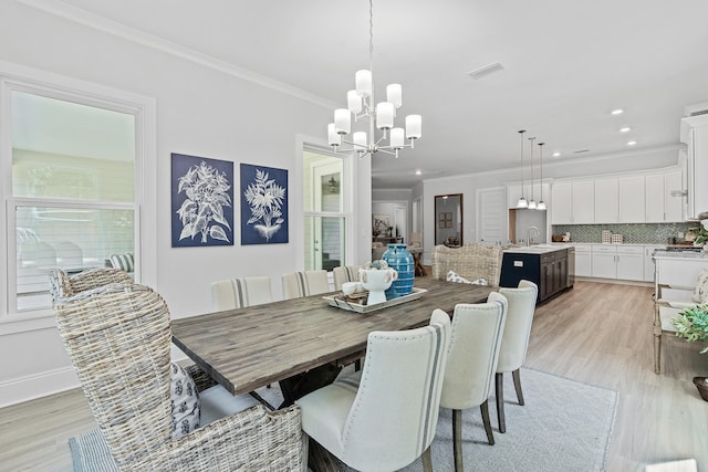 dining area featuring sink, a notable chandelier, crown molding, and light hardwood / wood-style flooring