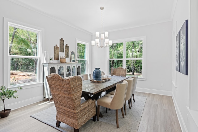 dining space with ornamental molding, a healthy amount of sunlight, light hardwood / wood-style floors, and a notable chandelier