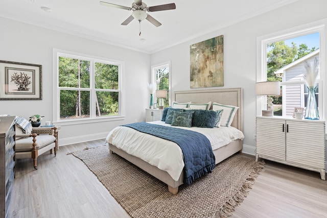 bedroom featuring ceiling fan, crown molding, light wood-type flooring, and multiple windows