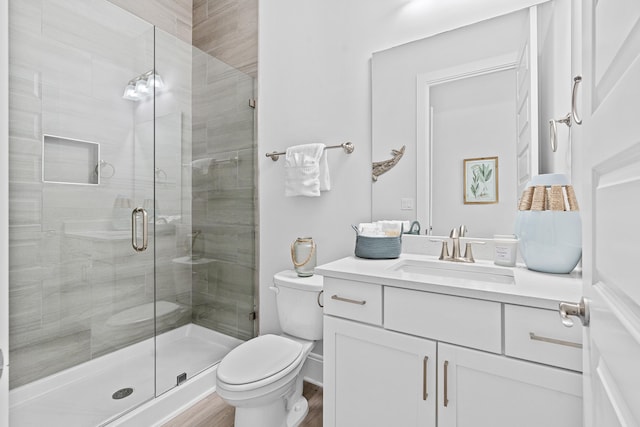 bathroom with toilet, an enclosed shower, wood-type flooring, and vanity