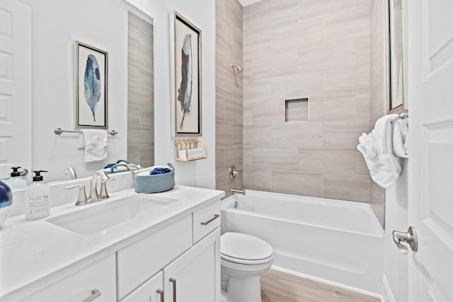 full bathroom with toilet, hardwood / wood-style flooring, tiled shower / bath combo, and vanity