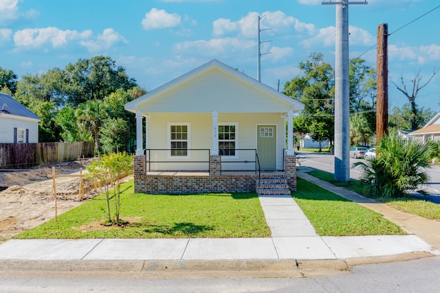 view of front of property with a porch, a front yard, and fence