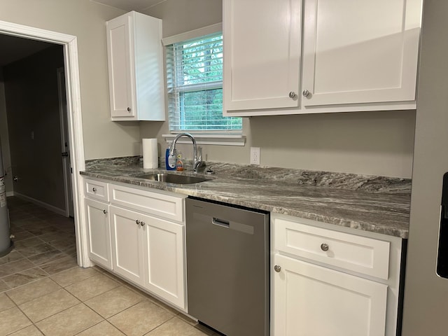 kitchen with white cabinets, sink, light tile patterned floors, stainless steel dishwasher, and dark stone countertops