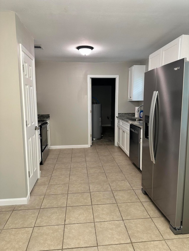 kitchen with stainless steel appliances, water heater, light tile patterned floors, sink, and white cabinetry