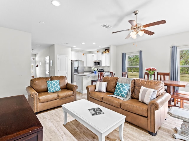 living room with ceiling fan, plenty of natural light, and light hardwood / wood-style flooring