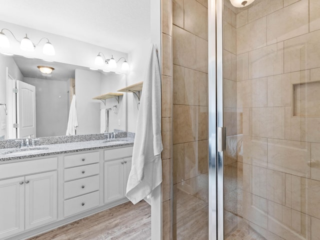 bathroom with a shower with door, vanity, and wood-type flooring