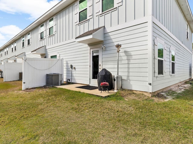 rear view of property featuring a lawn and cooling unit