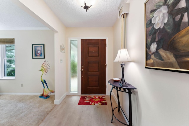 entryway featuring crown molding, a textured ceiling, and light hardwood / wood-style flooring