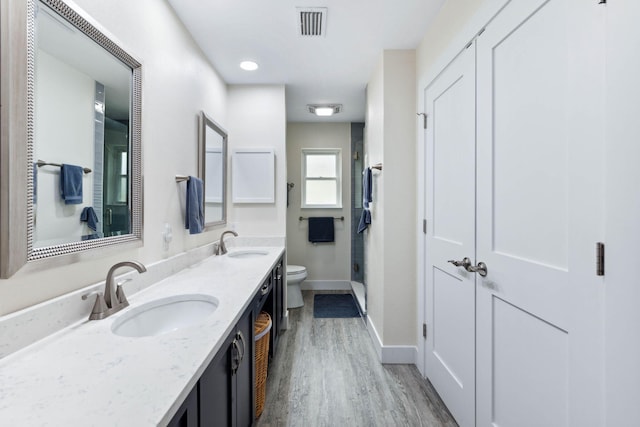 bathroom with vanity, hardwood / wood-style flooring, toilet, and a shower with door