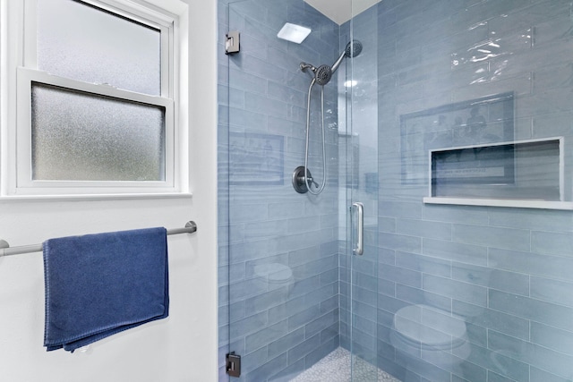 bathroom with a shower with shower door and toilet