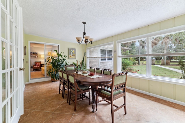 dining room featuring a textured ceiling, a notable chandelier, and light tile patterned flooring