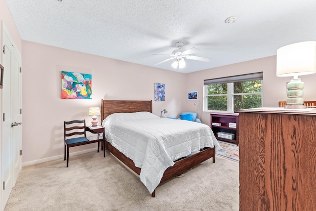 bedroom featuring light carpet, a textured ceiling, and ceiling fan