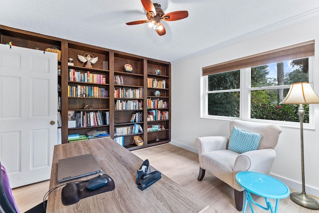 living area with ceiling fan, crown molding, light wood-type flooring, and a textured ceiling