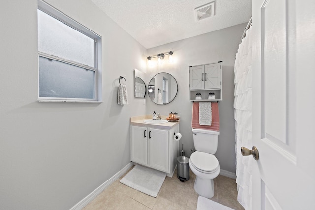 bathroom featuring toilet, vanity, a textured ceiling, and tile patterned floors