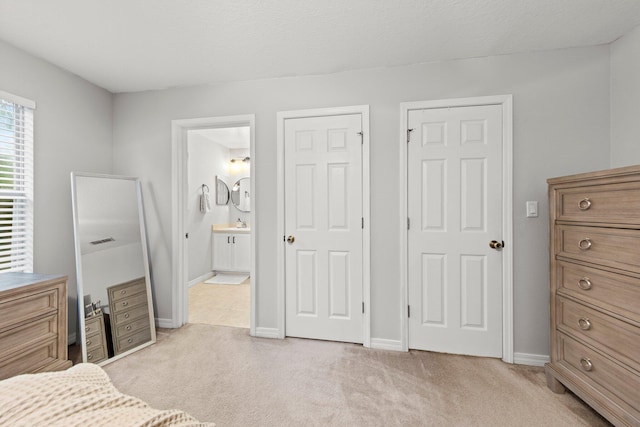 bedroom with light colored carpet, connected bathroom, and a textured ceiling