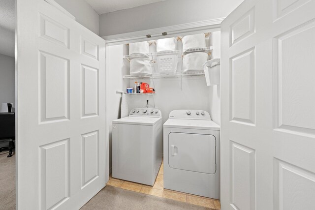 laundry room featuring washing machine and clothes dryer and light tile patterned floors