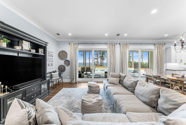 living area featuring recessed lighting, visible vents, an inviting chandelier, ornamental molding, and wood finished floors