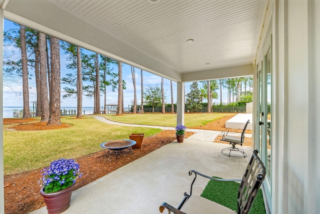 view of patio featuring a water view and fence