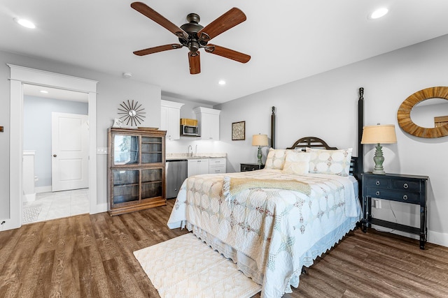 bedroom featuring a sink, baseboards, wood finished floors, and recessed lighting