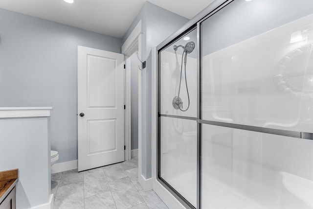 bathroom with baseboards, a shower stall, and toilet